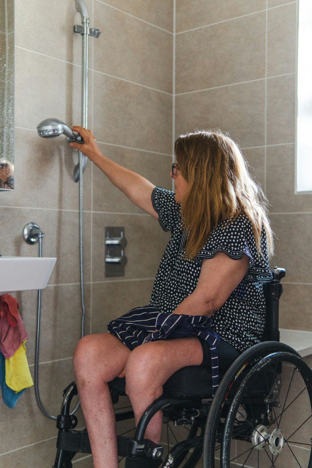 Woman using a handheld shower head in an accessible shower