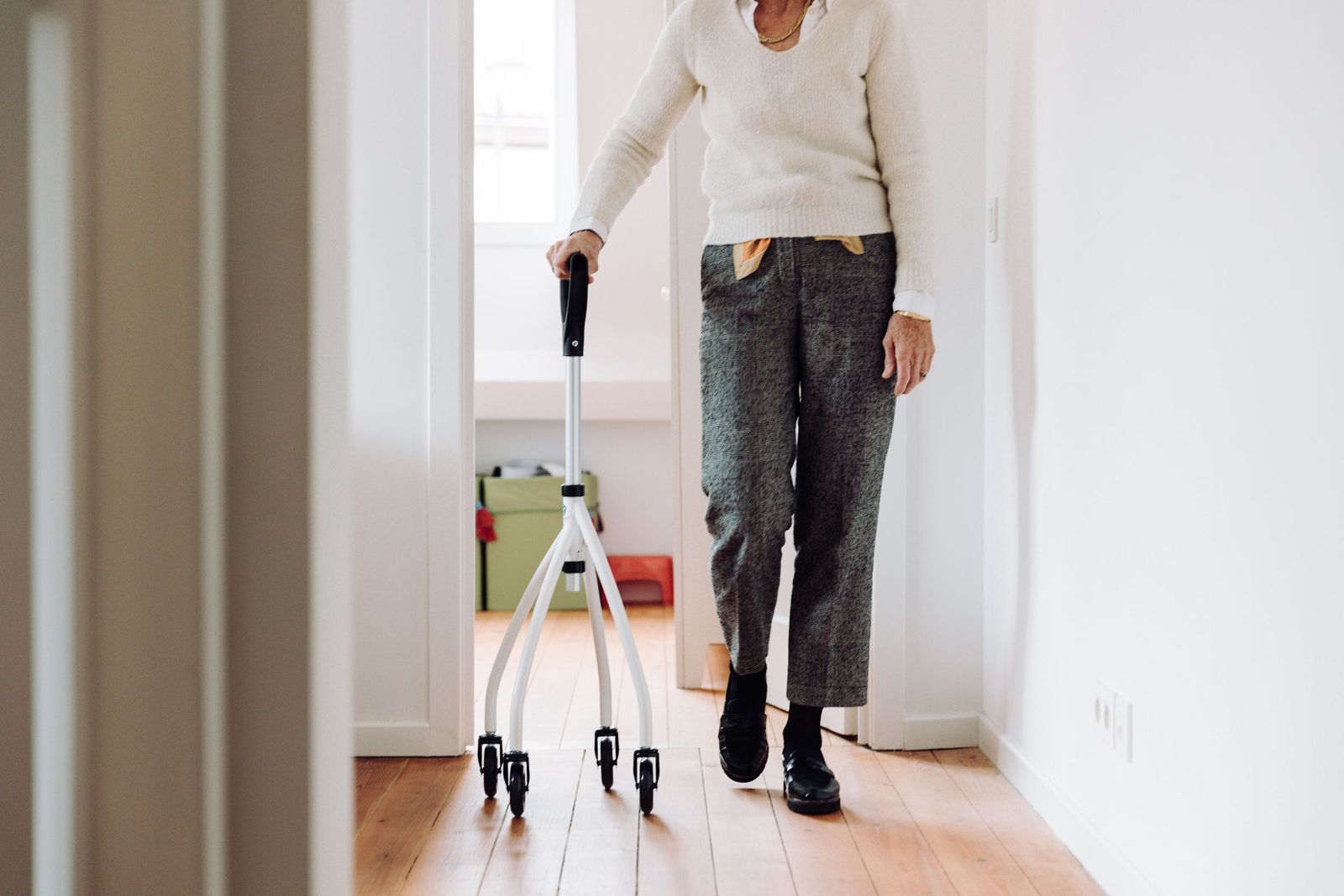 Older adult walking with a walker down a bright, clear hallway